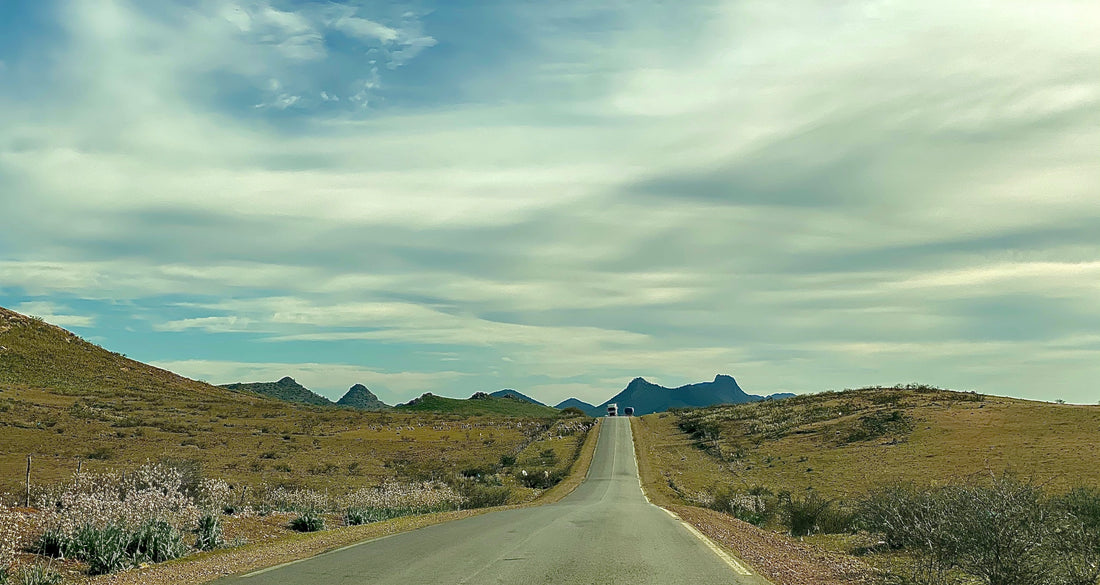 Two-lane road running through the dry Moroccan landscape toward the mountains