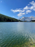 Calm lake with mountains and buildings in the distance.