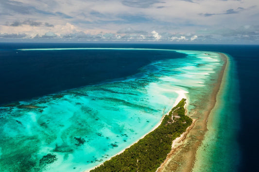 Aerial view of a Maldives local island with a long sandbank and shallow turquoise water